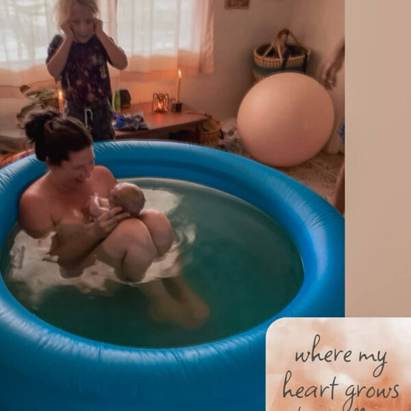 home birth mother holding newborn in birth pool smiling